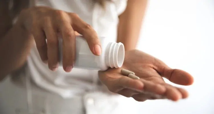 Zena stavlja kapsule na ruku iz bocice
