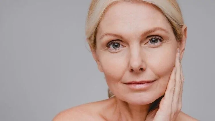 Starija žena drži se rukom za lice i ima zdravu i lijepu kožu bez bora zahvaljujući Beauty Harmony kolagenu