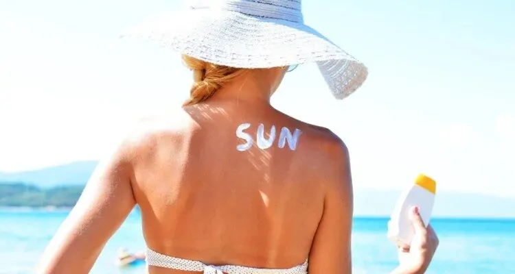 Zena s natpisom "Sun" napisanim s kremom za suncanje