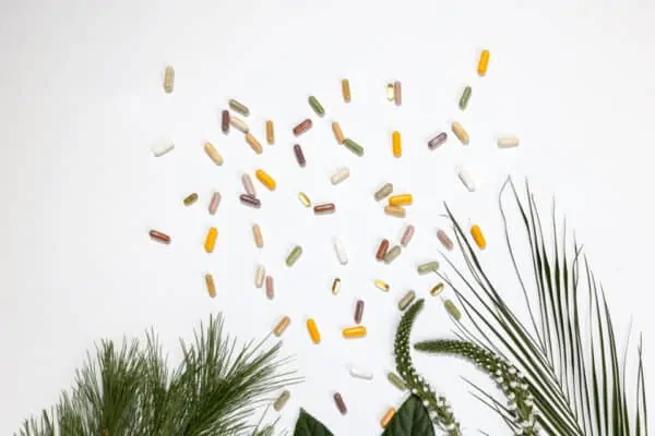 Kapsule Hug Your Life dodataka prehrani na bijelol pozadini s biljkama