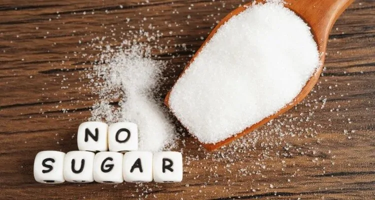 Secer u drvenoj zlici pored bijelih kockica na kojima pise "no sugar"