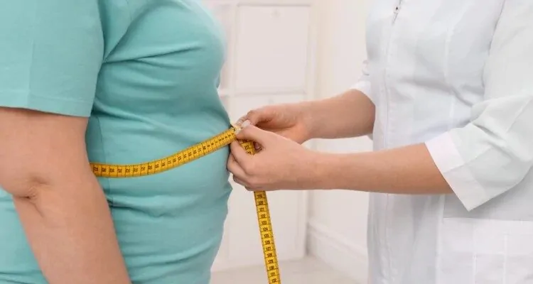 Pretilost Medicinska sestra mjeri struk pacijentu s metrom te ukazuje na pretilost