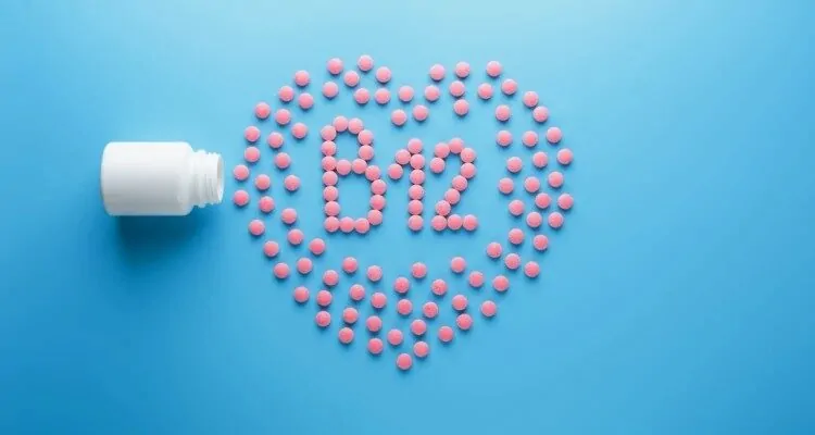 Crvene tabletice poslozene u obliku srca i unutar njega ispisano "B12" s istim tabletama